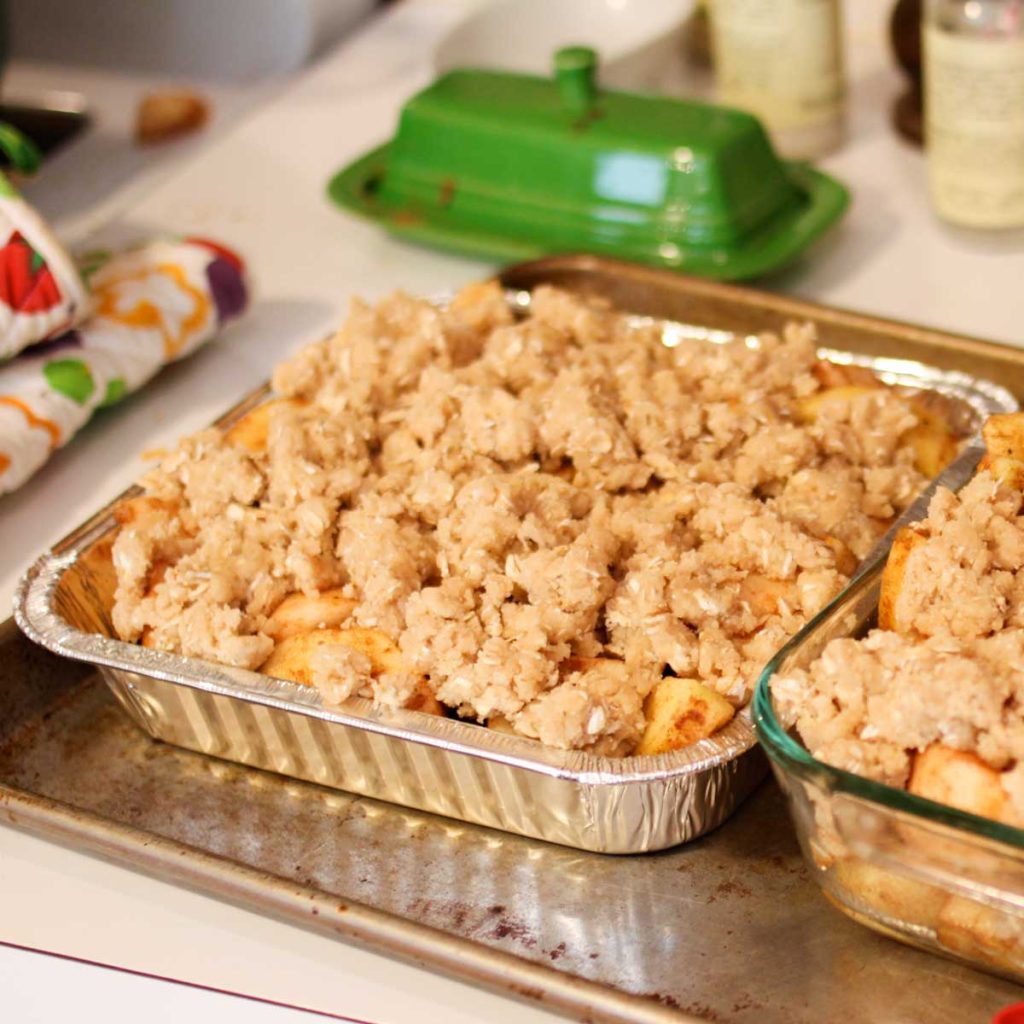 An apple crisp is in a foil pan and ready to go in the freezer.