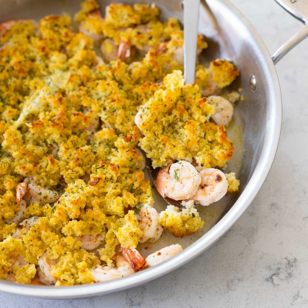 A skillet of baked shrimp scampi with breadcrumbs on top.