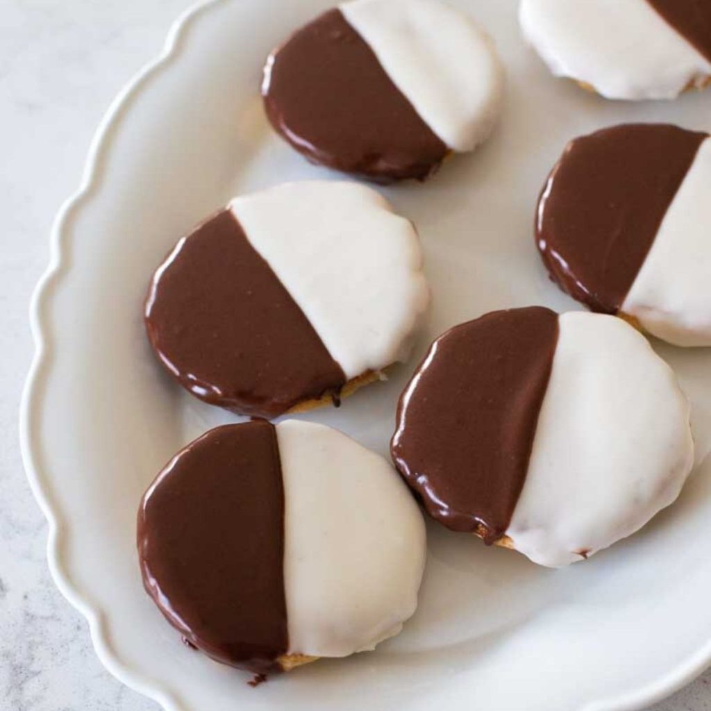 A white platter is filled with NYC black and white cookies.