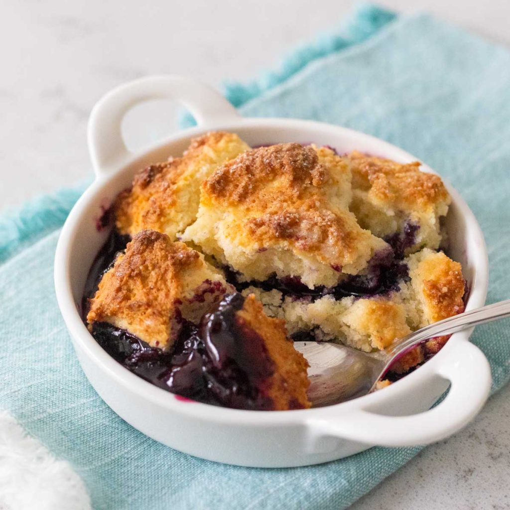 A white dish filled with blueberry cobbler.
