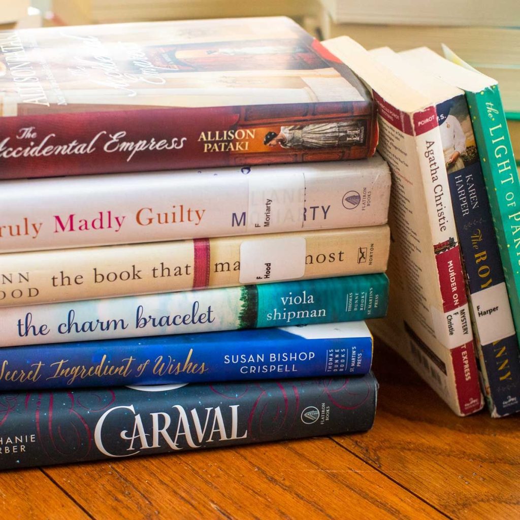 A stack of books fresh from the library are stacked on the table.