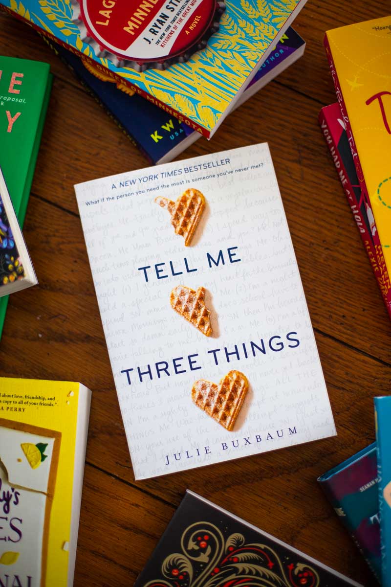 A copy of the book Tell Me Three Things is on the table.