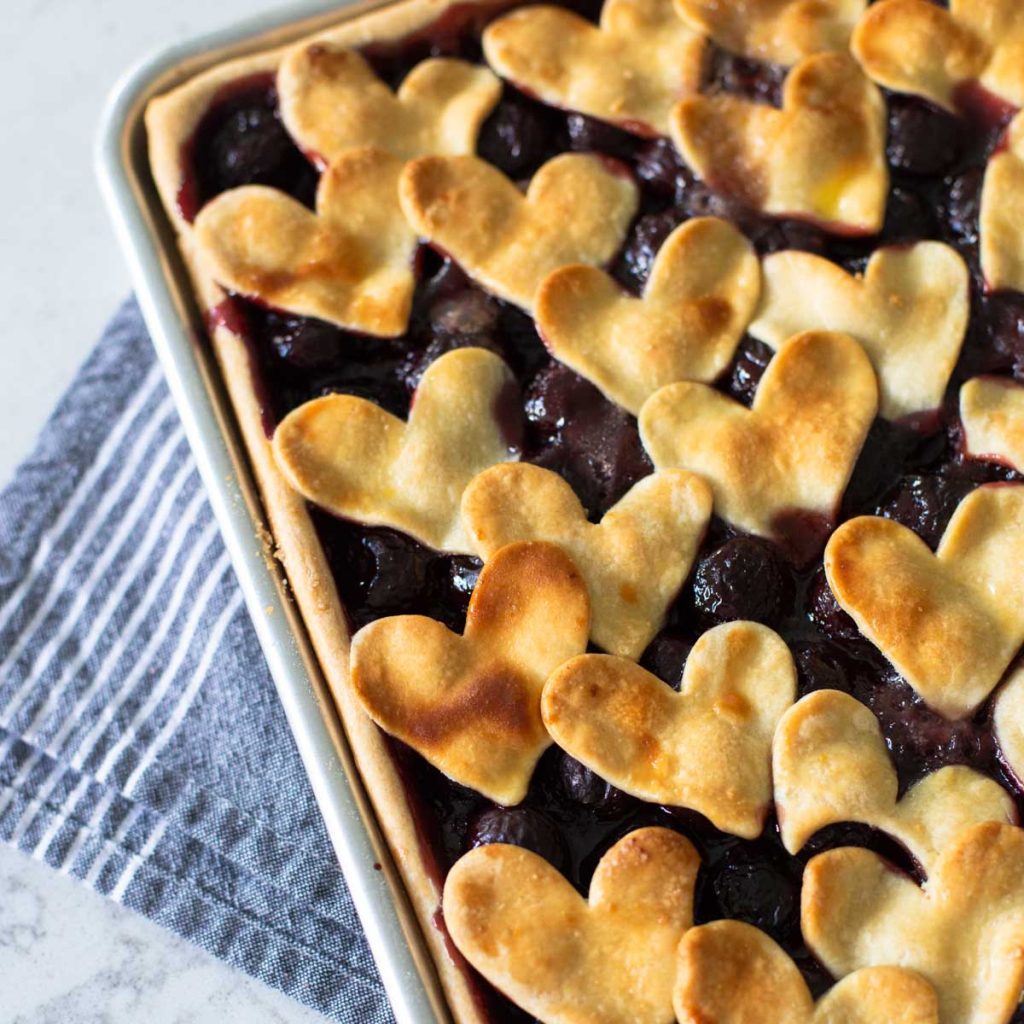 A cherry pie has the top crust baked with heart-shaped cut outs.
