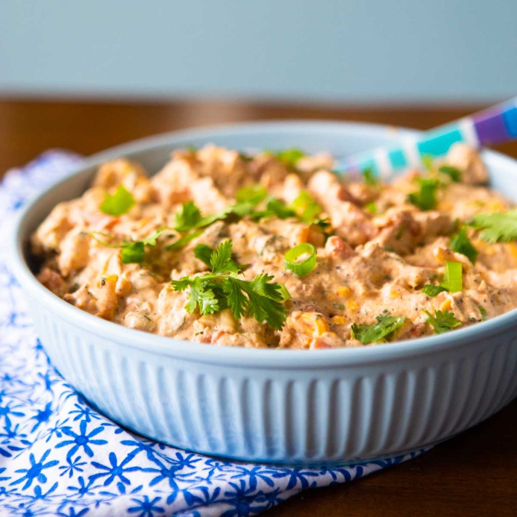 A blue bowl filled with cream chicken enchilada dip and fresh cilantro on top.