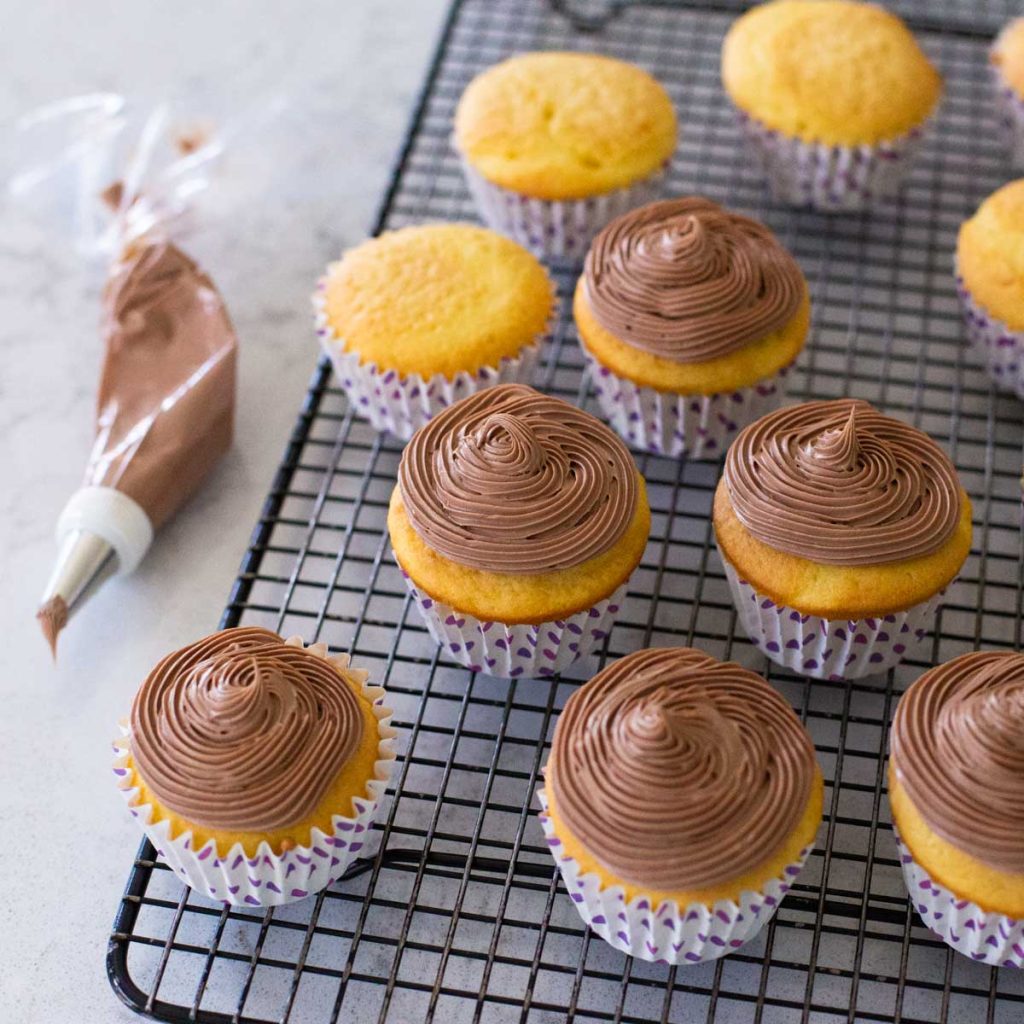 a batch of cupcakes have chocolate cream cheese frosting on them.
