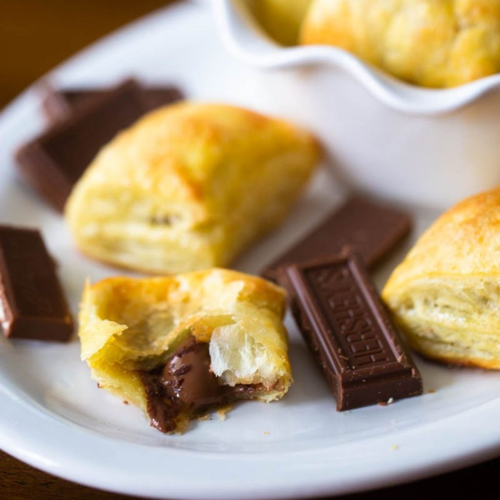 Chocolate filled puff pastry bites on a white platter.