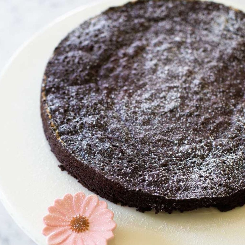 A dark chocolate torte sits on a cake platter.