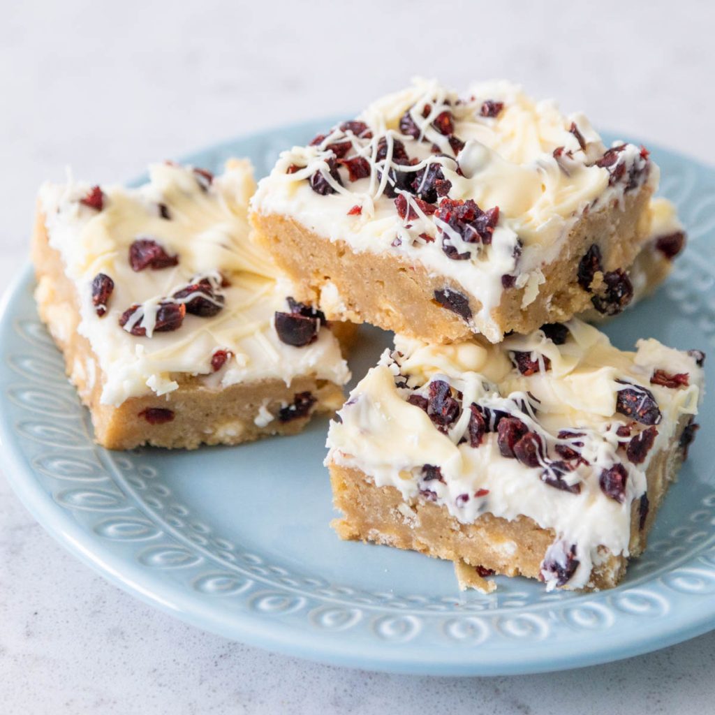 White chocolate covered cranberry cookie bars on a blue plate.
