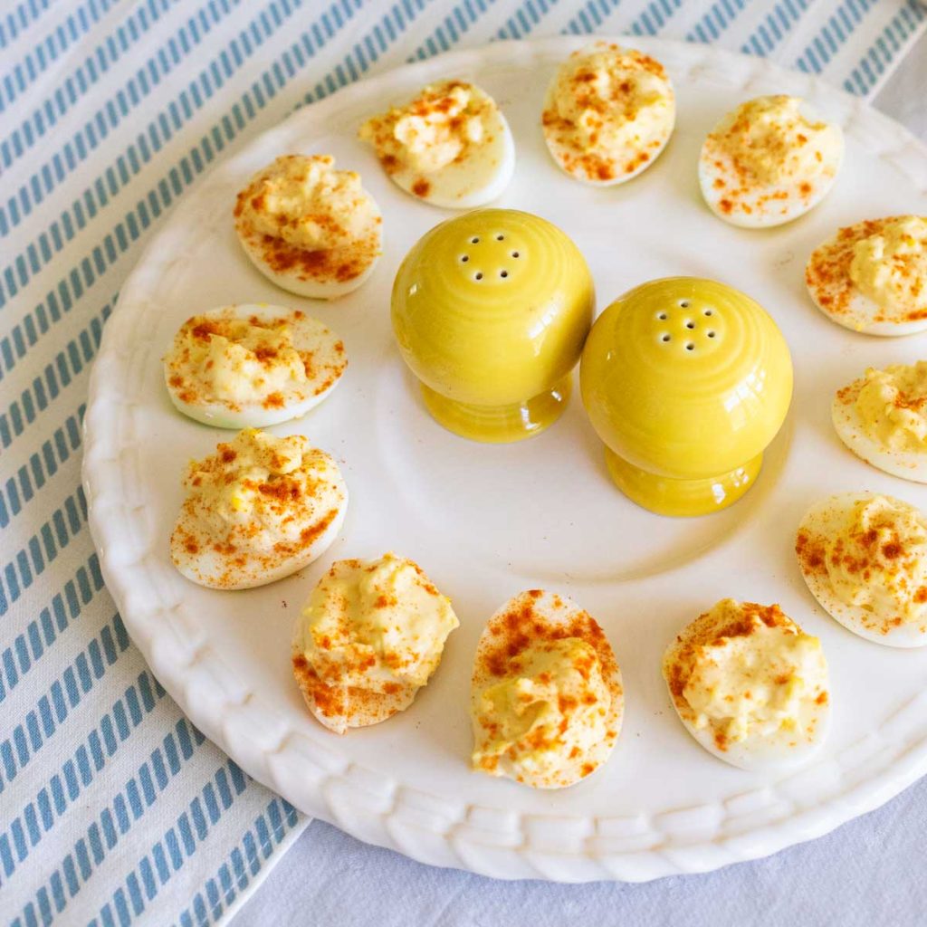 A platter of deviled eggs has yellow salt and pepper shakers in the middle.