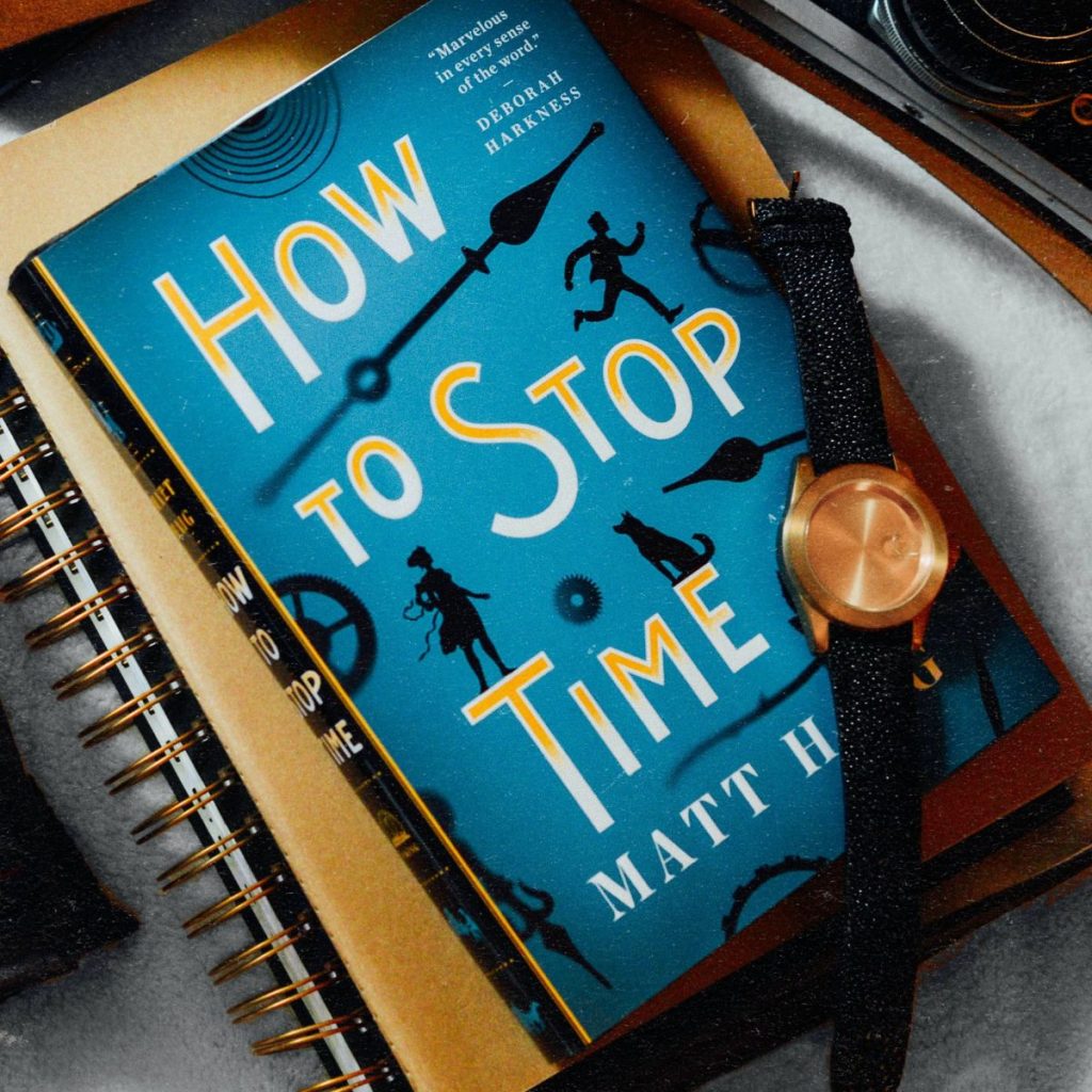 A copy of "How to Stop Time" sits on top of a notebook.