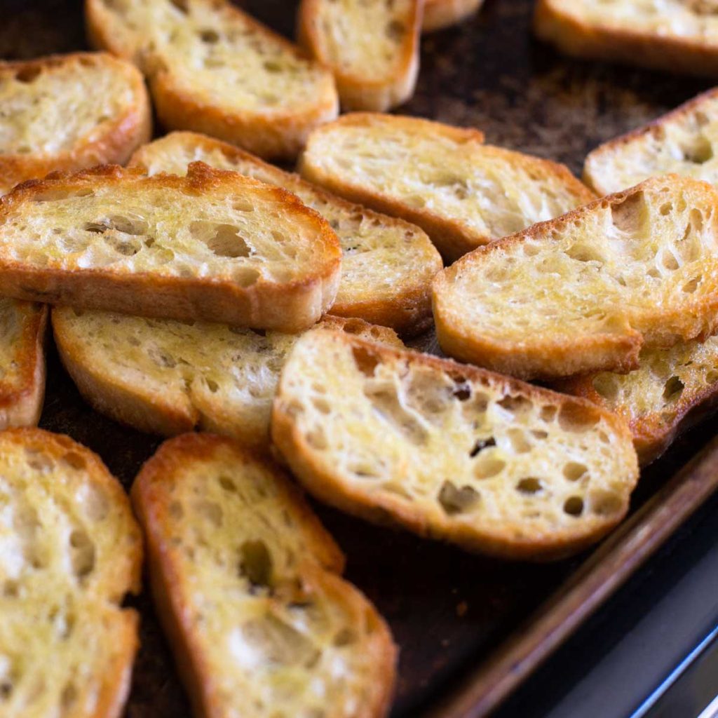A baking pan has fresh crostini just out of the oven.