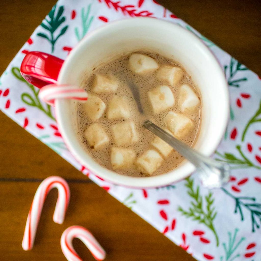 A mug of hot cocoa with marshmallows and candy canes.