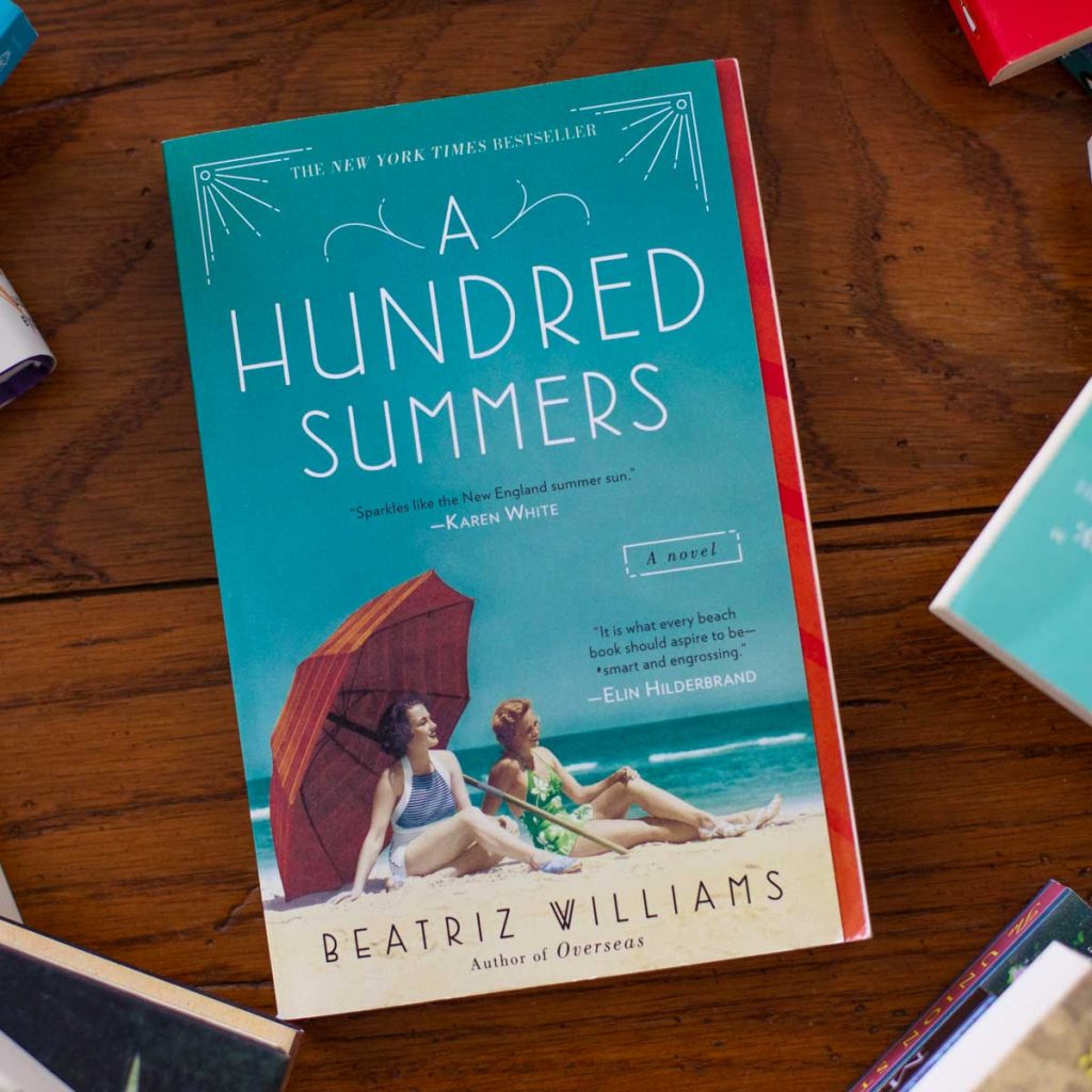 A copy of the book A Hundred Summers sits on a table.