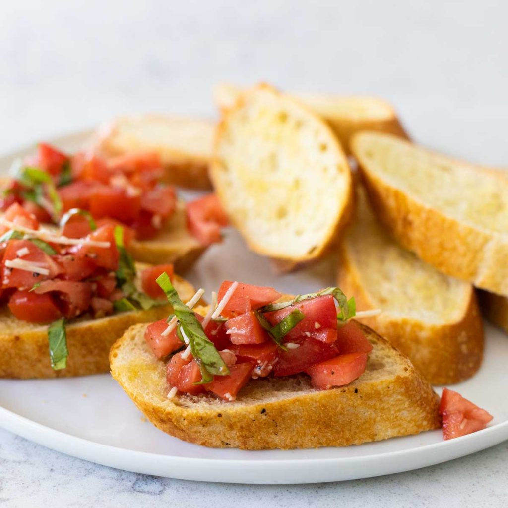 A tomato topped crostini toast with fresh basil.