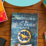 A copy of the book Midnight at the Blackbird Cafe is on the table.