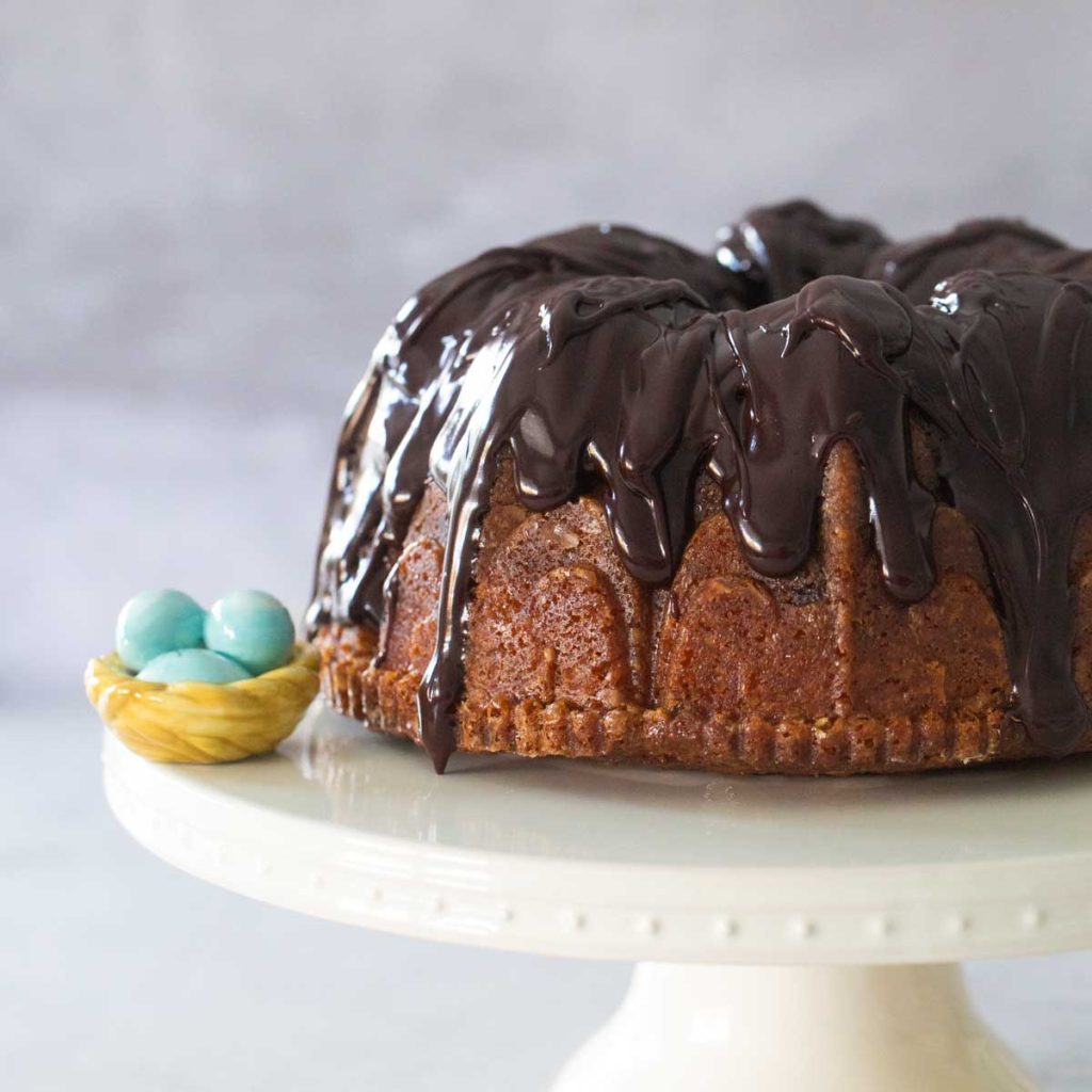 A chocolate covered bundt cake sits on a cake platter.