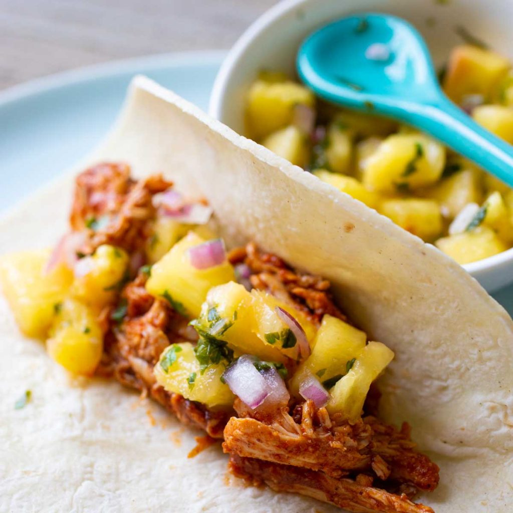 A fresh pineapple salsa has been spooned over a chicken taco.