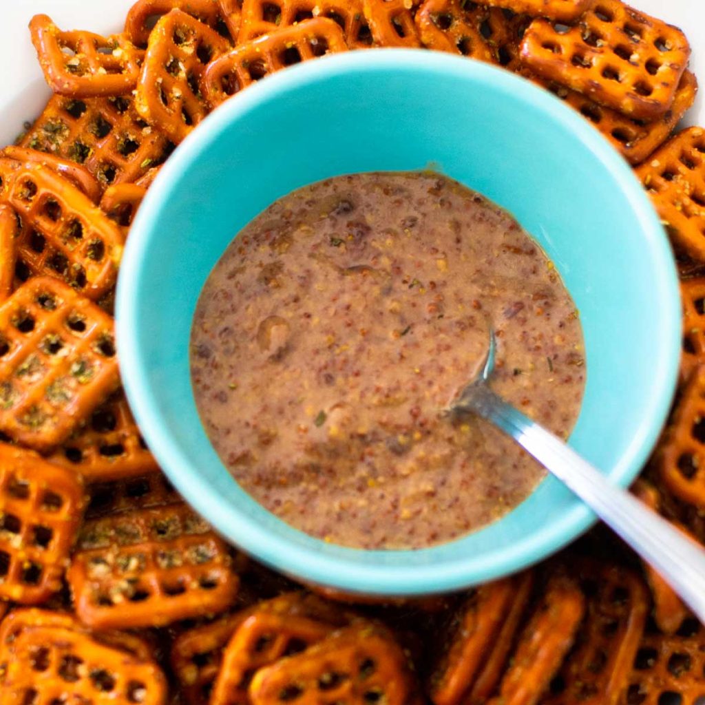 A bowl of raspberry mustard dip is nestled in a bowl of pretzels.