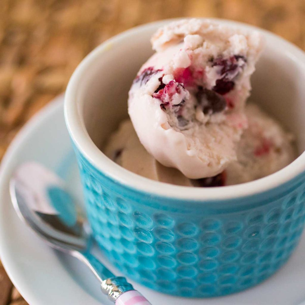 A cherry ice cream is in a blue bowl.