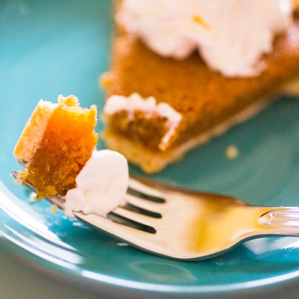A slice of treacle tart has a bite being cut off by a fork.