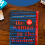 A copy of the book The Woman in the Window sits on a table.