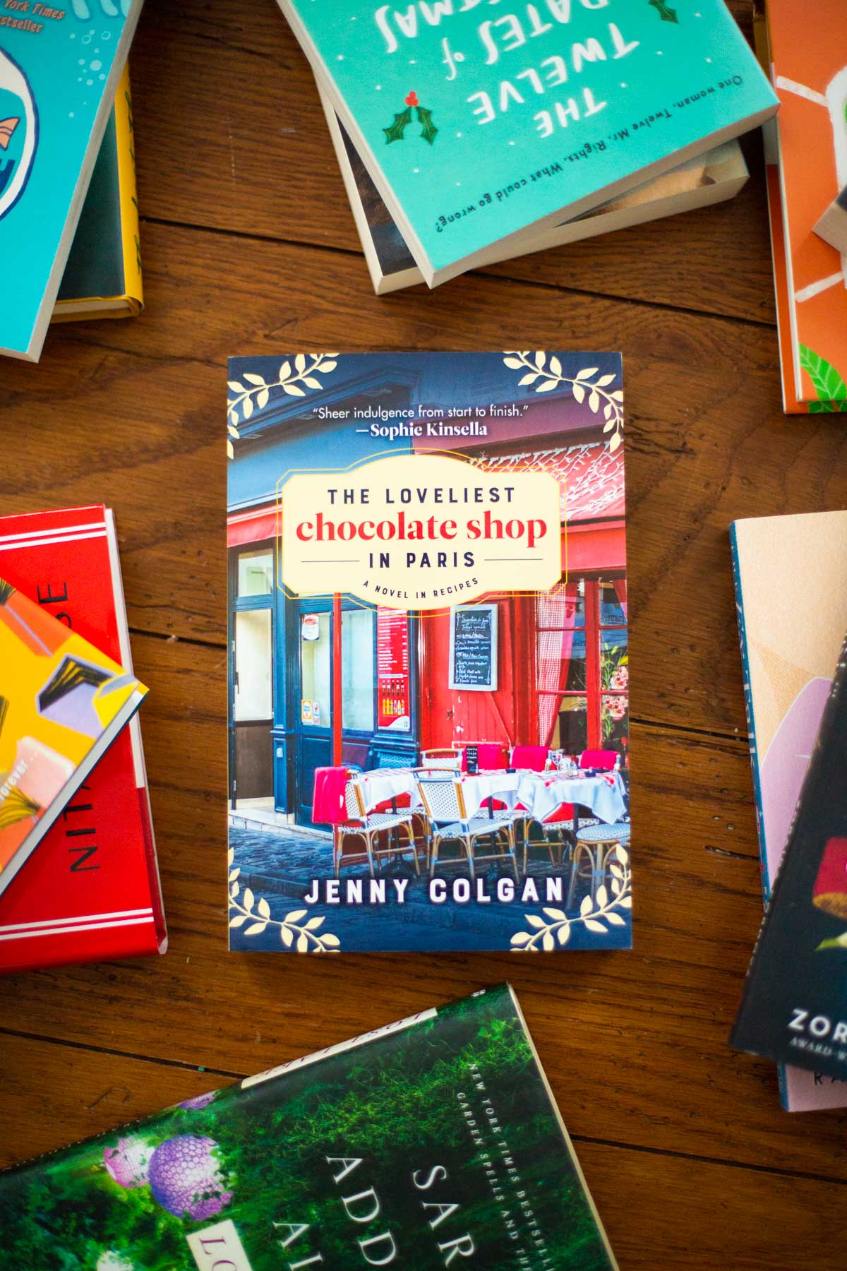 A copy of The Loveliest Chocolate Shop in Paris by Jenny Colgan sits on a table.