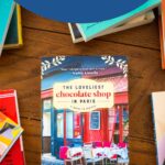 A copy of The Loveliest Chocolate Shop in Paris by Jenny Colgan sits on a table.