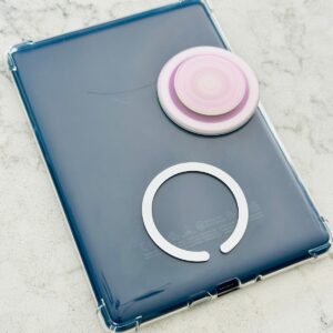 A lavender popsocket sits on the back of the Kindle. You can see the magnetic strip where it will stick on the bottom middle of the device.