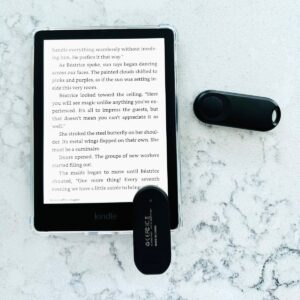 The page turner device has been clipped to the bottom of the Kindle reader while the remote button sits off to the side.