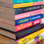 A stack of books from the new book club list sit on the table.