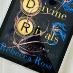 The book cover for Divine Rivals by Rebecca Ross is on the screen of an iPad.