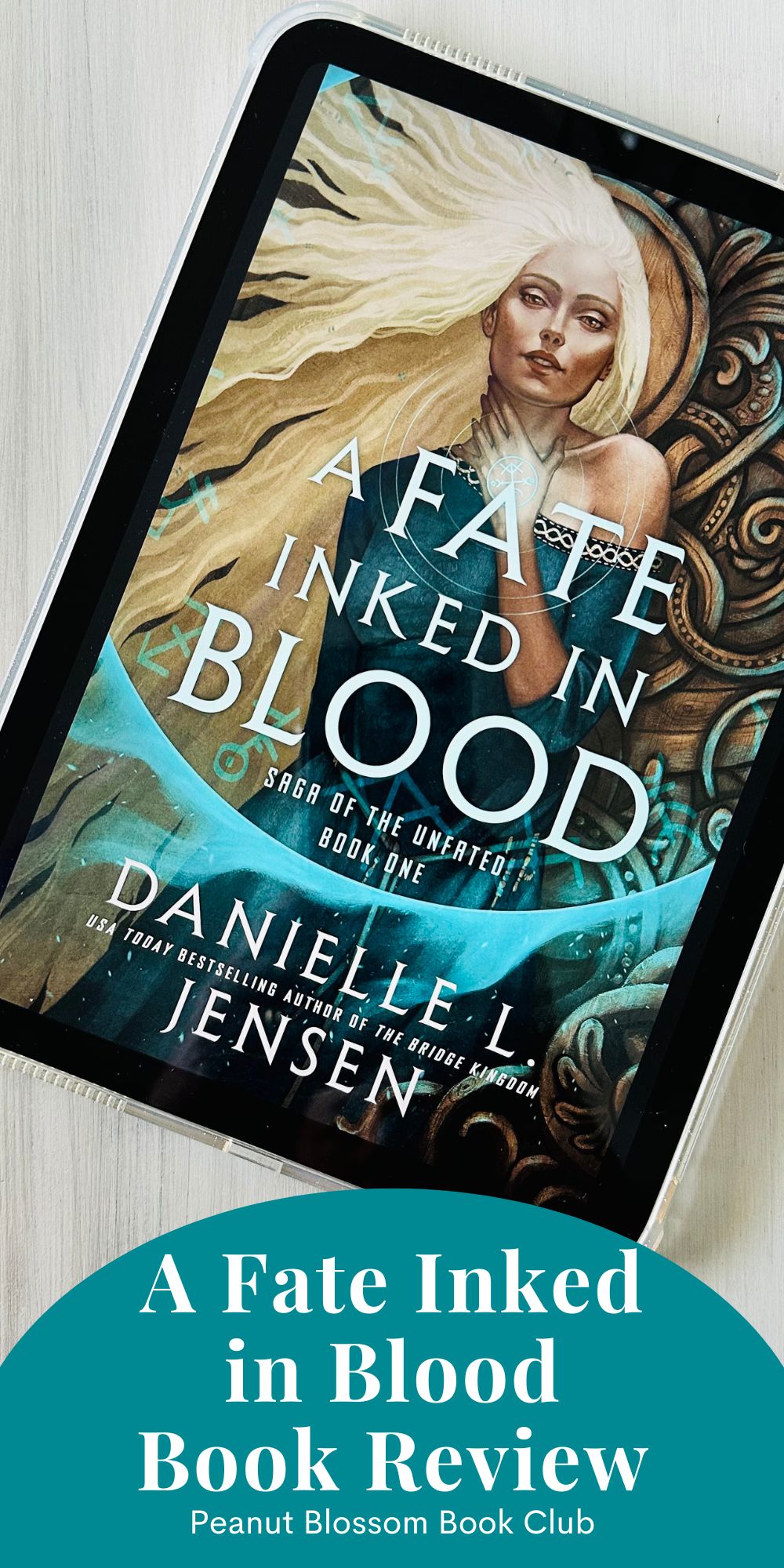 The cover of the book A Fate Inked in Blood by Danielle L. Jensen is on an iPad screen.