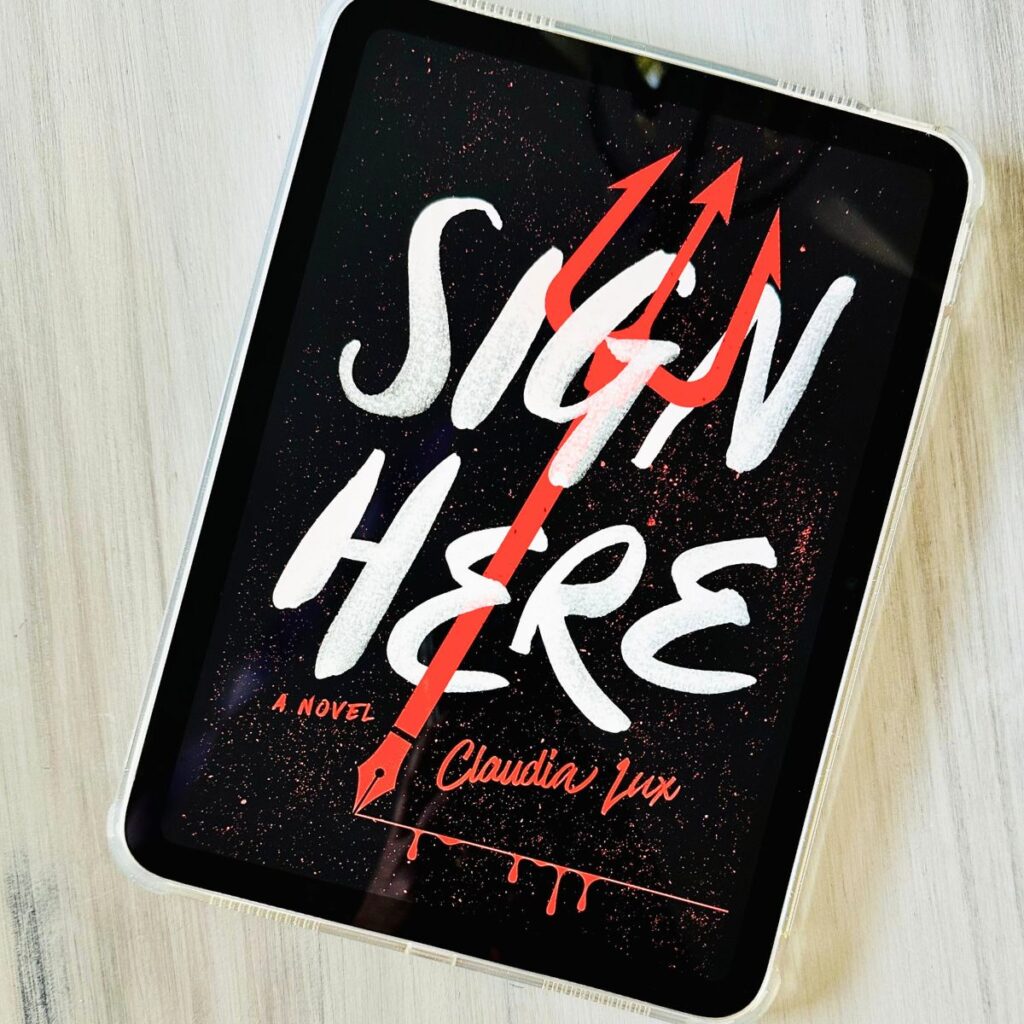 The cover of the book Sign Here by Claudia Lux is on the screen of an iPad.