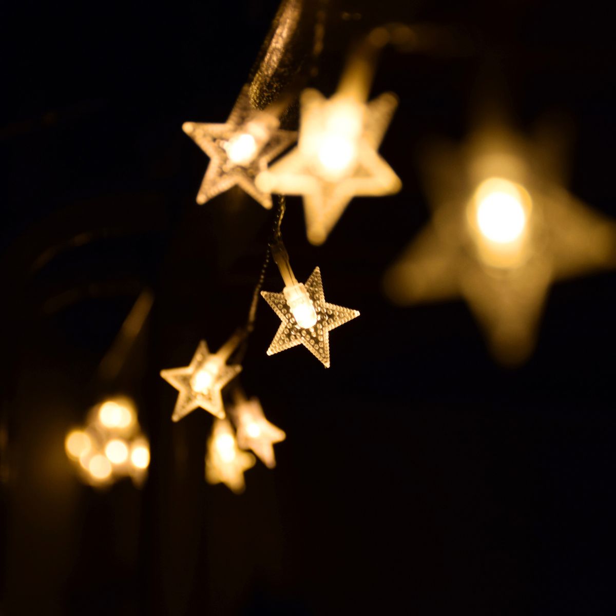 A string of star-shaped twinkle lights against a black background.