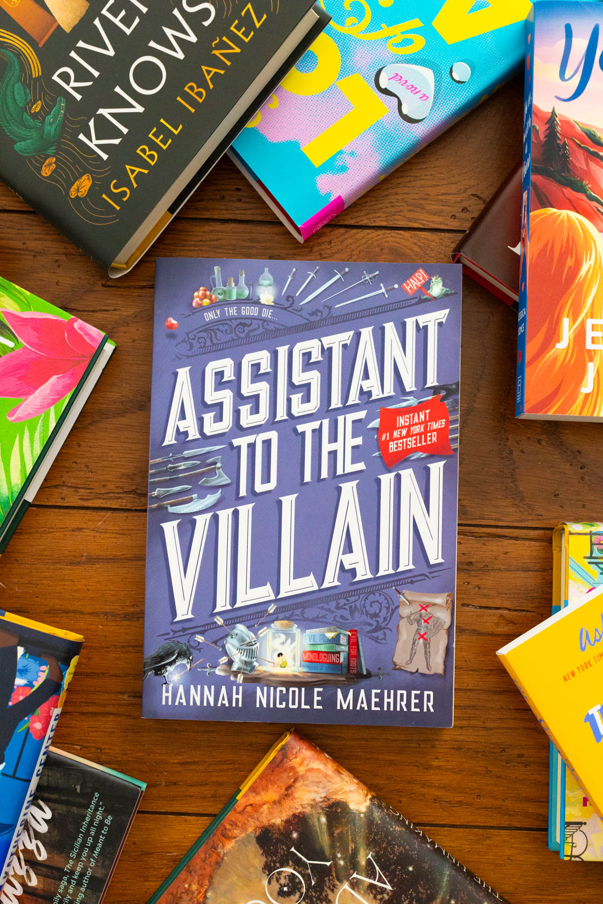 A copy of the book Assistant to the Villain by Hannah Nicole Maehrer sits on the table.