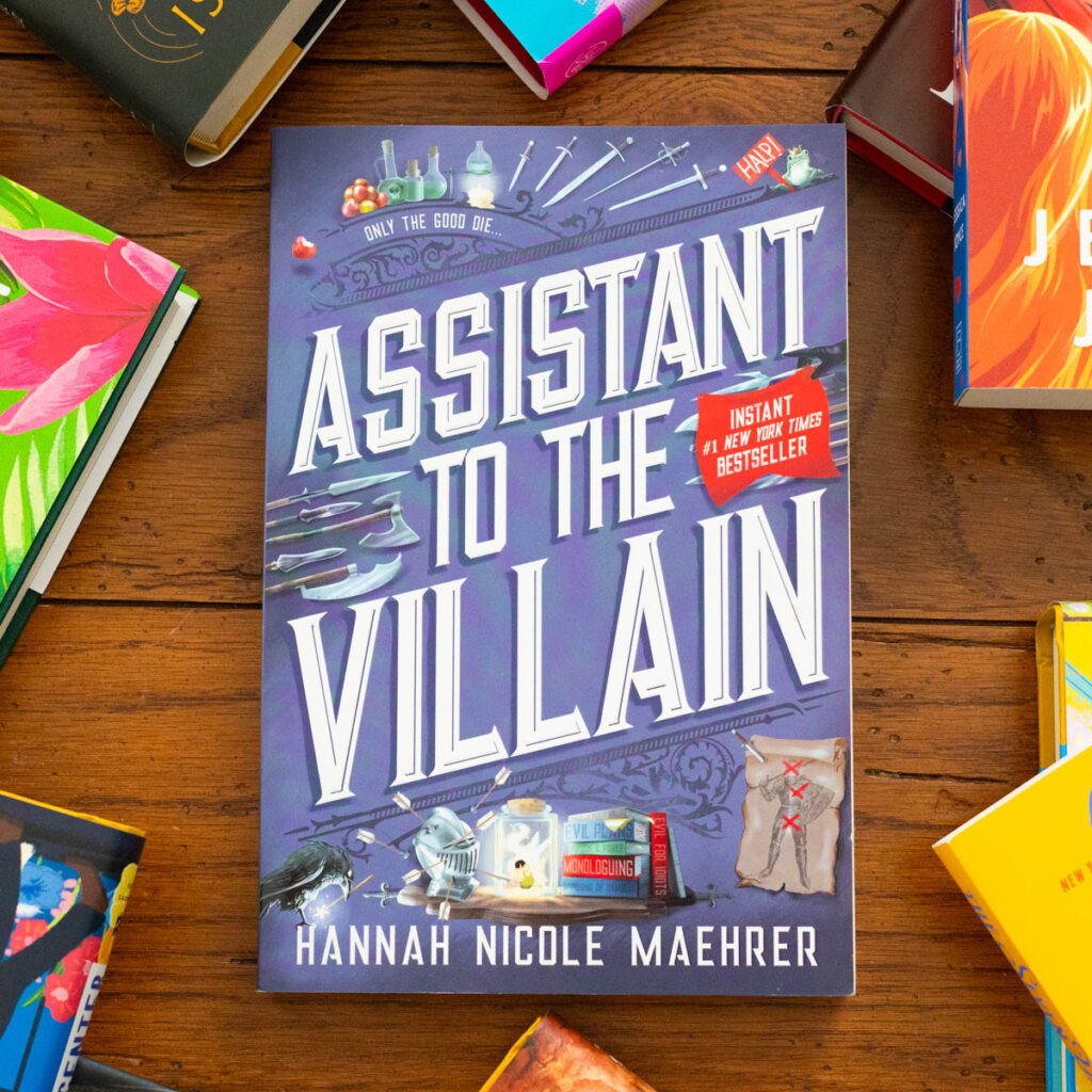 A copy of Assistant to the Villain by Hannah Nicole Maehrer sits on the table.