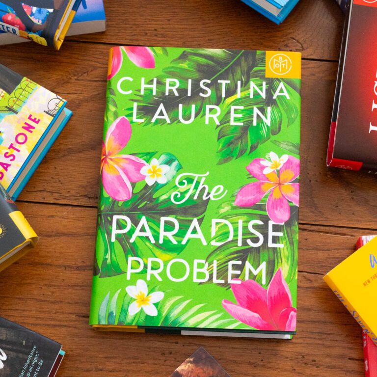 A copy of the book The Paradise Problem by Christina Lauren sits on the table.