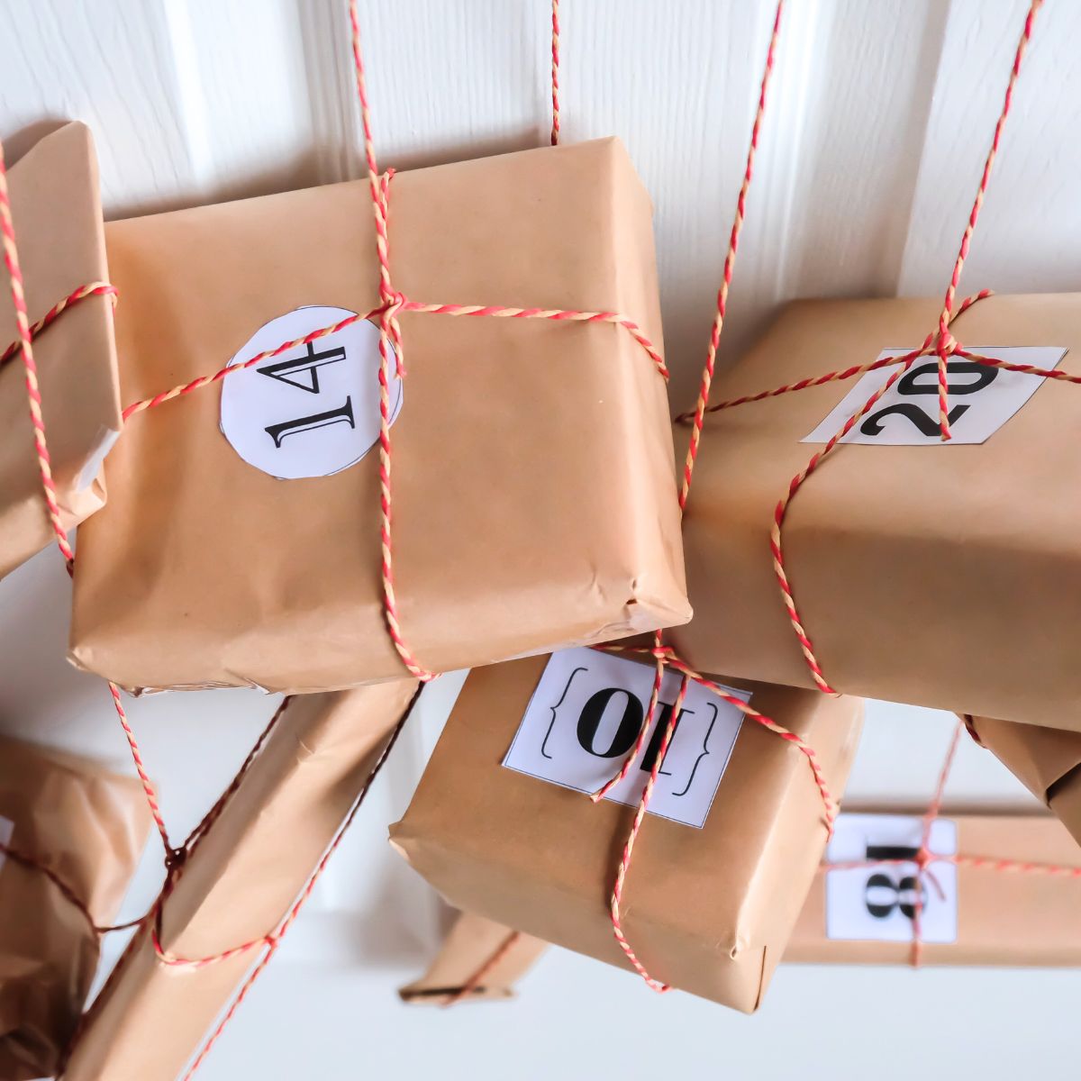 Several brown paper wrapped packages with numbers and tied up with red striped string.