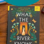 A copy of the book What the River Knows by Isabel Ibanez sits on the table.