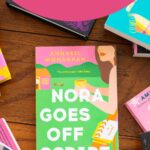 A copy of the book Nora Goes Off Script is on the table.