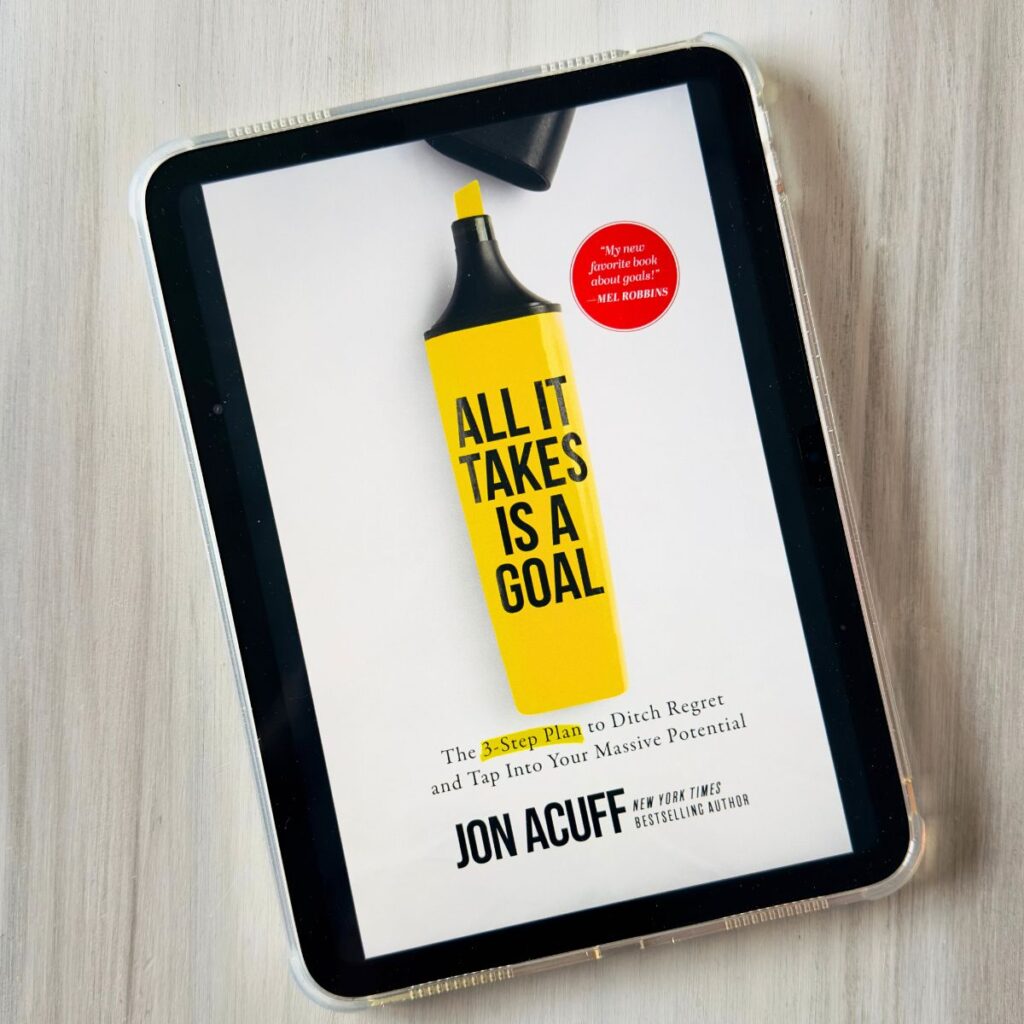 The cover of All It Takes is a Goal by Jon Acuff is on the screen of an ipad.