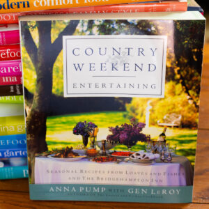 A copy of Country Weekend Entertaining by Anna Pump rests against a stack of cookbooks.