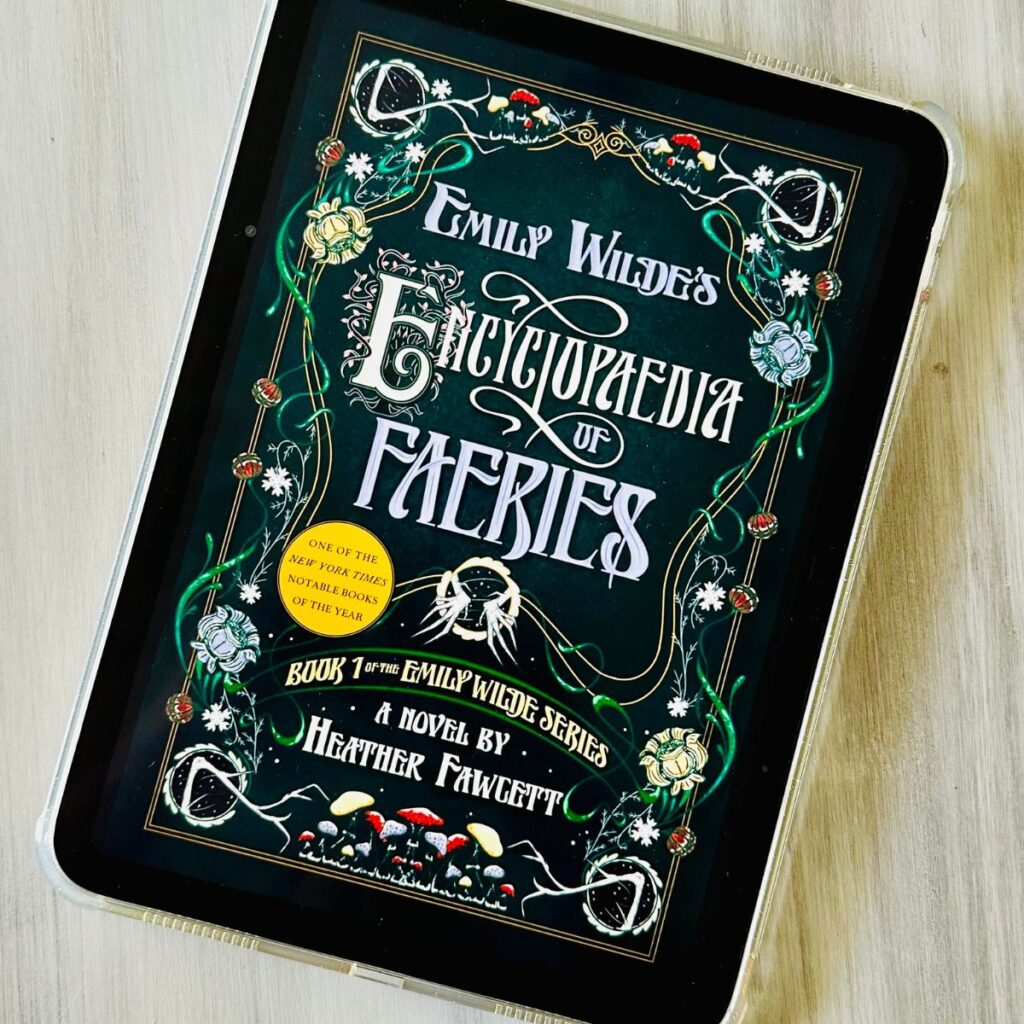 The cover of the book Emily Wilde's Encyclopaedia of Faeries by Heather Fawcett is on the screen of an iPad.