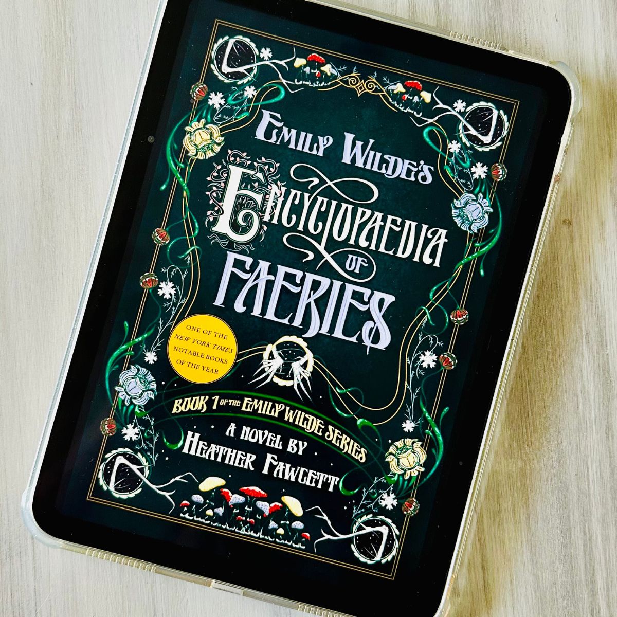 The cover of the book Emily Wilde's Encyclopaedia of Faeries by Heather Fawcett is on the screen of an iPad.