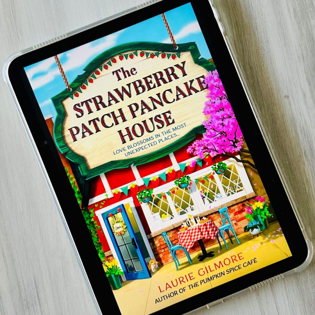 The cover of the book The Strawberry Patch Pancake House by Laurie Gilmore is on the screen of an ipad.