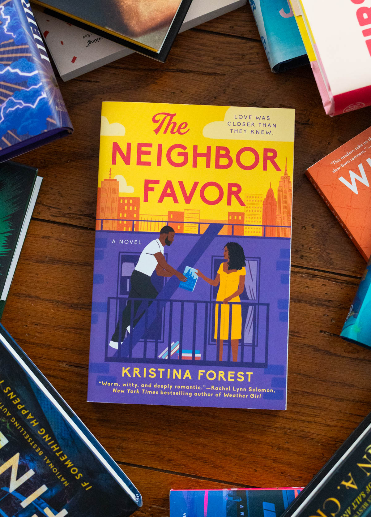 A copy of The Neighbor Favor by Kristina Forest sits on the table.